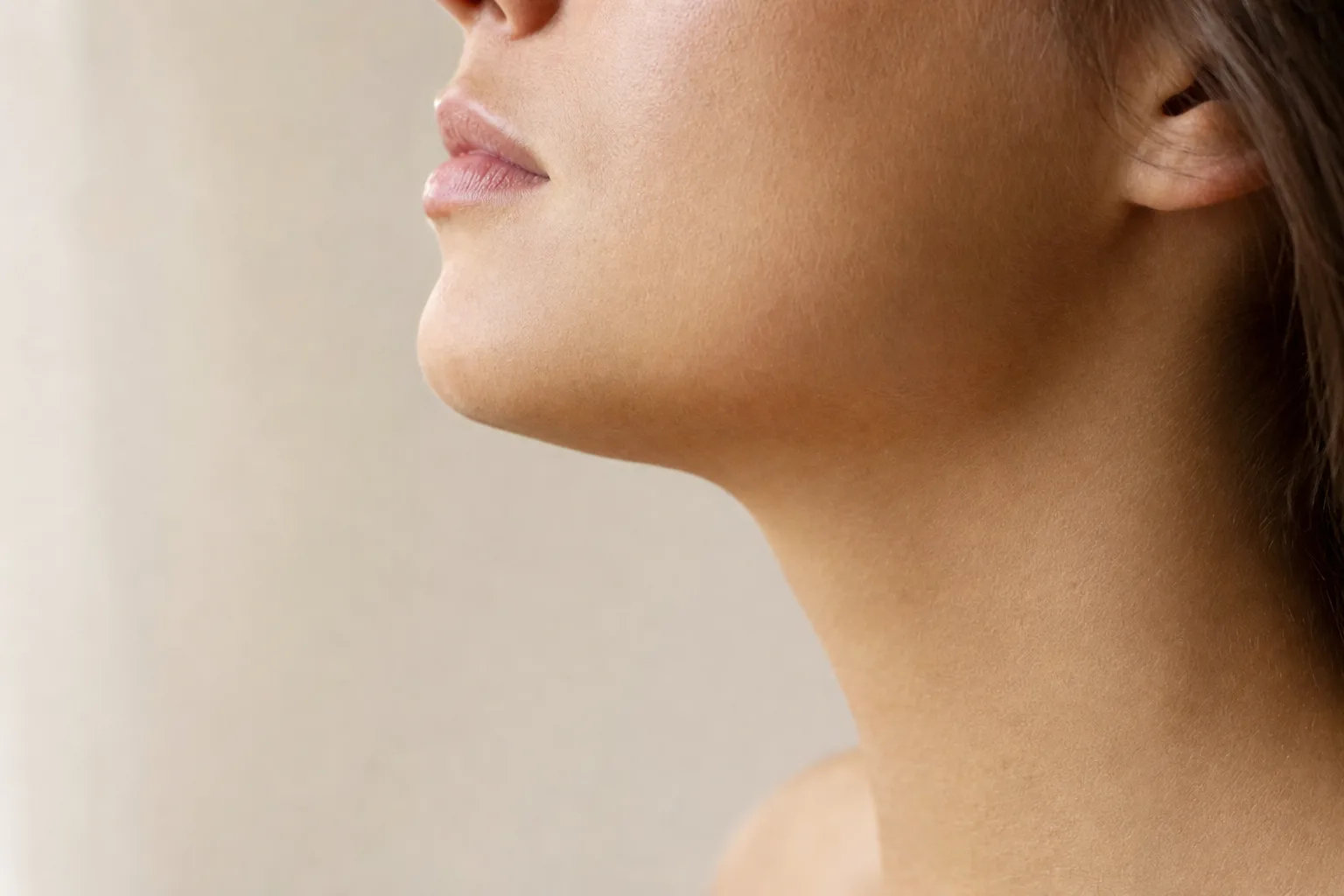 Illustrative close-up of a woman's jawline and chin in soft window light