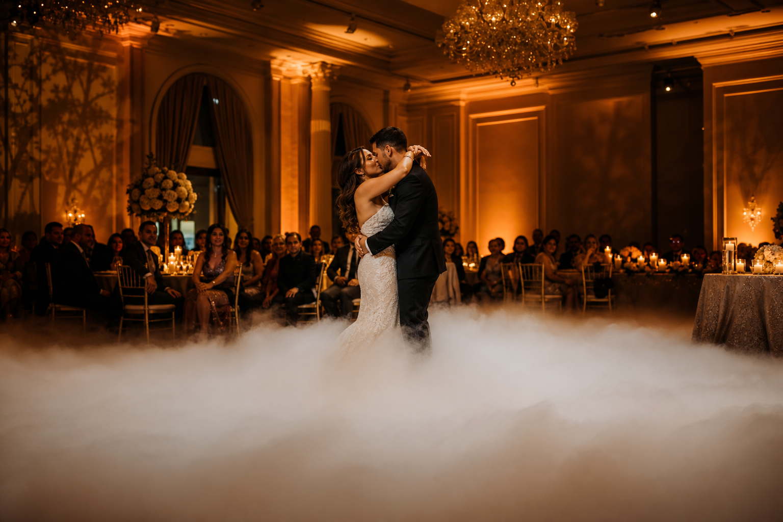 Wedding reception with dry ice fog cloud spreading across dance floor as a couple shares their first dance under warm uplighting