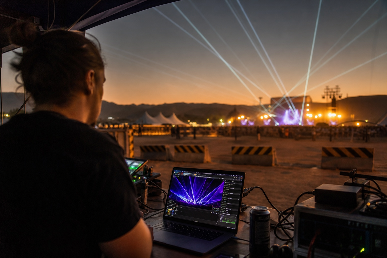 Laser show control booth with operator at console monitoring beam paths during outdoor performance