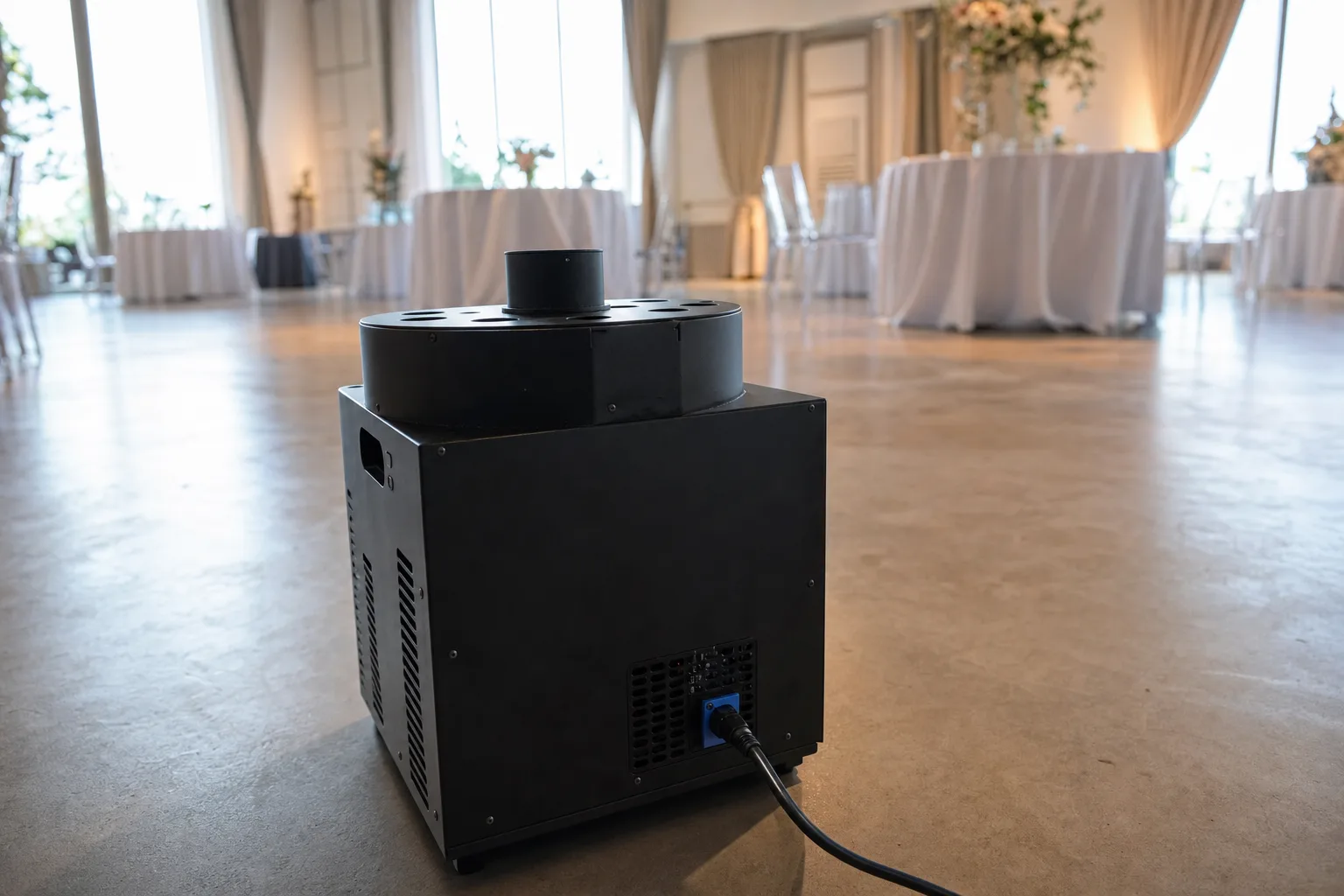 Illustration: a compact cold spark machine sitting on the floor of an empty event room before guests arrive